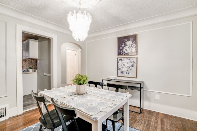 17215 Warrington Dr, Detroit, MI 48221 - dining space featuring an inviting chandelier, arched walkways, dark wood-style floors, and a textured ceiling