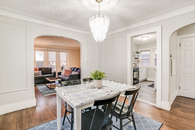 17215 Warrington Dr, Detroit, MI 48221 - dining area featuring a textured ceiling, arched walkways, wood finished floors, baseboards, and a chandelier