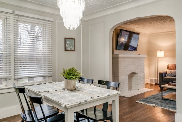 17215 Warrington Dr, Detroit, MI 48221 - dining area with a fireplace, arched walkways, a textured ceiling, a healthy amount of sunlight, and wood finished floors