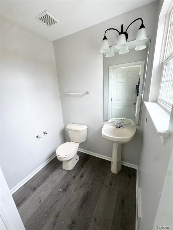 half bathroom featuring visible vents, baseboards, wood finished floors, and toilet