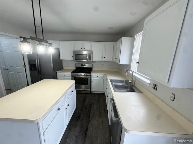 kitchen featuring appliances with stainless steel finishes, a sink, white cabinetry, a kitchen island, and dark wood-style floors