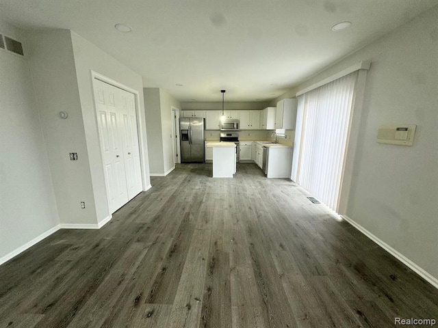 unfurnished living room with dark wood-style flooring, baseboards, visible vents, and a sink