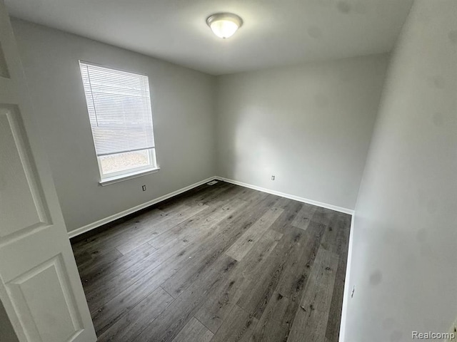 spare room with baseboards and dark wood finished floors