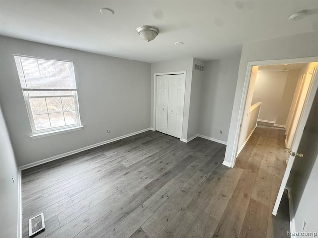 unfurnished bedroom with baseboards, dark wood-style flooring, and visible vents