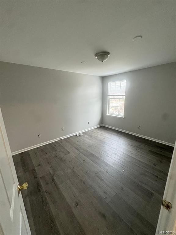 empty room with baseboards and dark wood-style floors
