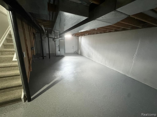 unfinished basement featuring heating unit and stairway
