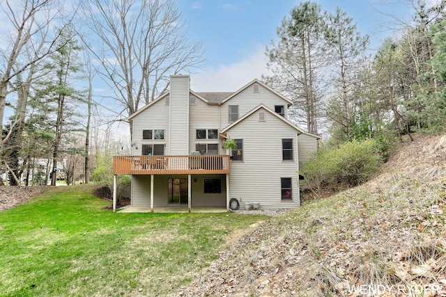 back of property with a yard, a deck, a chimney, and a patio