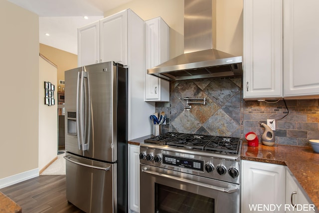 kitchen featuring dark wood-style flooring, wall chimney exhaust hood, appliances with stainless steel finishes, and white cabinetry