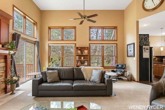 carpeted living area featuring a ceiling fan and a towering ceiling