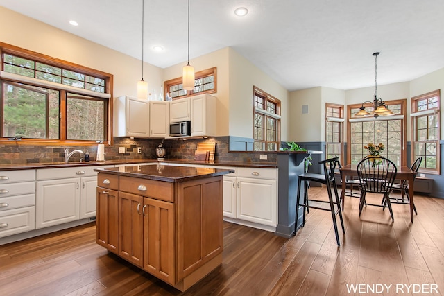 kitchen featuring plenty of natural light, white cabinetry, and stainless steel microwave