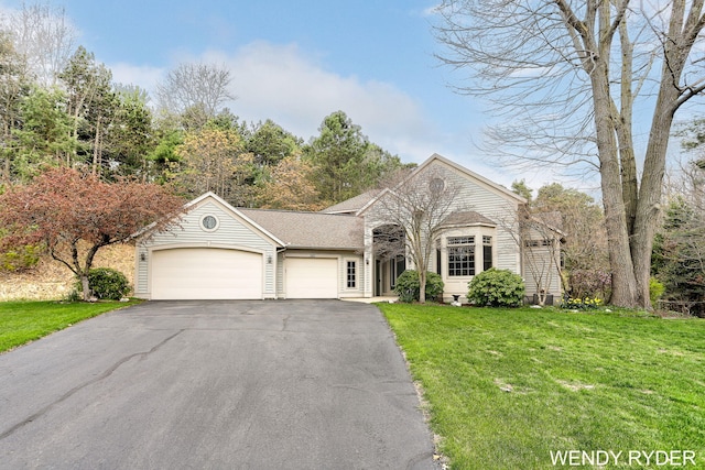 ranch-style house featuring a shingled roof, an attached garage, driveway, and a front yard