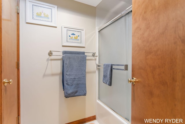 bathroom with baseboards and shower / bath combination with glass door