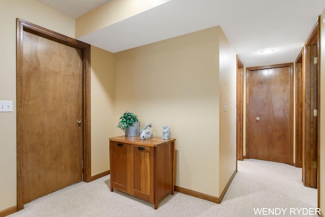 hall with light colored carpet and baseboards