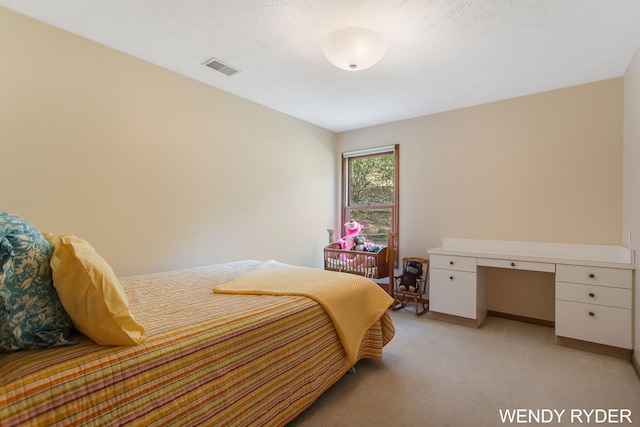 bedroom with baseboards, light colored carpet, built in desk, and visible vents