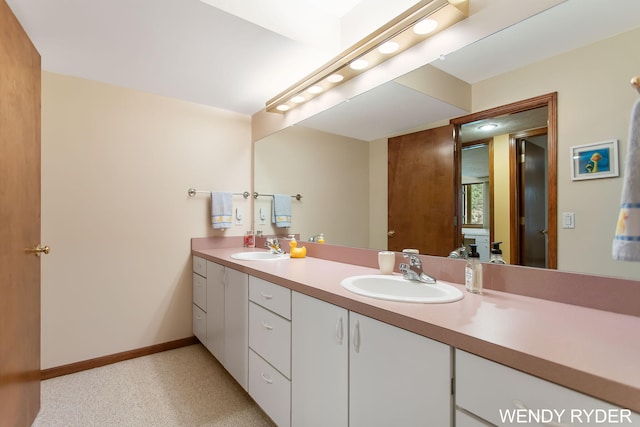 bathroom with a sink, baseboards, and double vanity