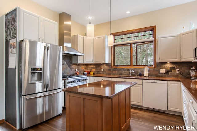 kitchen with a sink, stainless steel appliances, dark wood finished floors, and wall chimney exhaust hood
