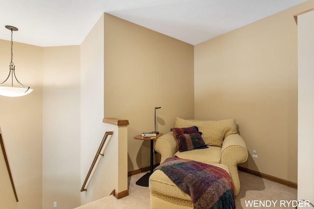 living area with light colored carpet, baseboards, and an upstairs landing