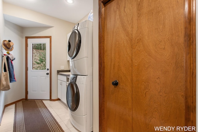 laundry area featuring cabinet space, light tile patterned flooring, recessed lighting, baseboards, and stacked washer and clothes dryer