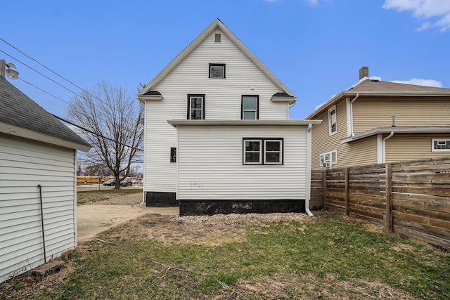 rear view of property featuring a yard and fence