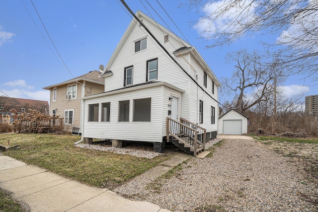 view of side of property with entry steps, an outbuilding, gravel driveway, and a detached garage
