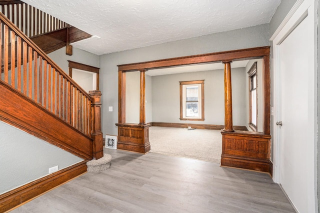 foyer entrance with a textured ceiling, visible vents, wood finished floors, stairway, and baseboards