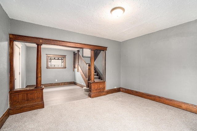 carpeted empty room featuring stairway, baseboards, and a textured ceiling