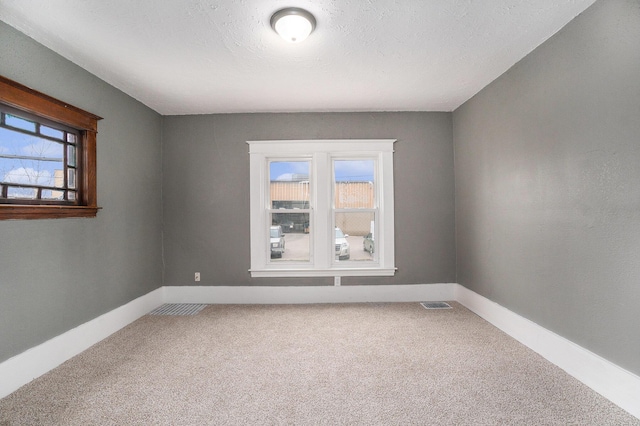 carpeted spare room with baseboards and visible vents