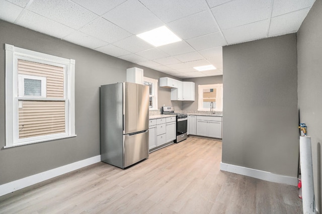 kitchen featuring baseboards, appliances with stainless steel finishes, a paneled ceiling, and light wood-style floors