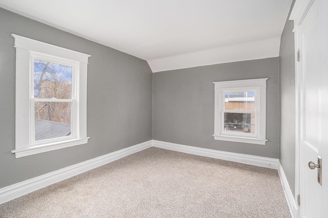 carpeted spare room with baseboards, a healthy amount of sunlight, and lofted ceiling