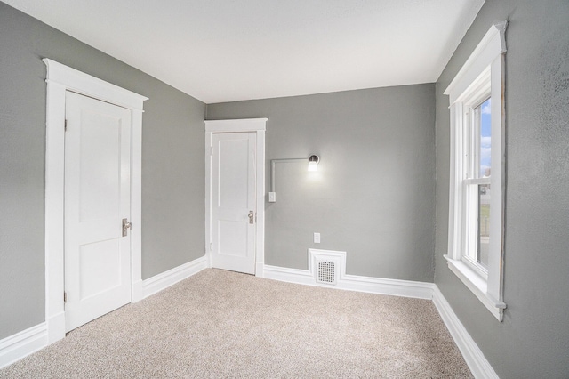 carpeted spare room featuring baseboards and visible vents