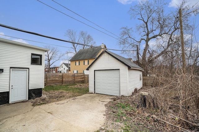 detached garage with fence and concrete driveway
