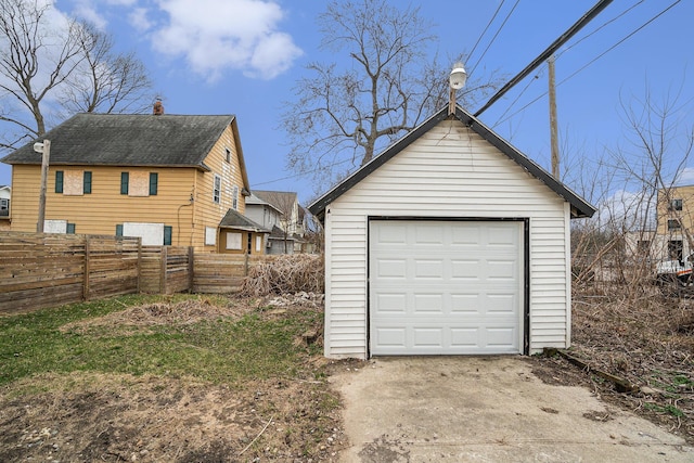 detached garage featuring fence and concrete driveway