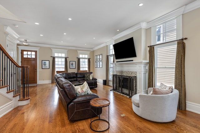 living area with recessed lighting, a fireplace, wood finished floors, and stairway
