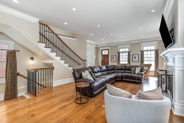 living area featuring crown molding, recessed lighting, a high end fireplace, and light wood-style floors