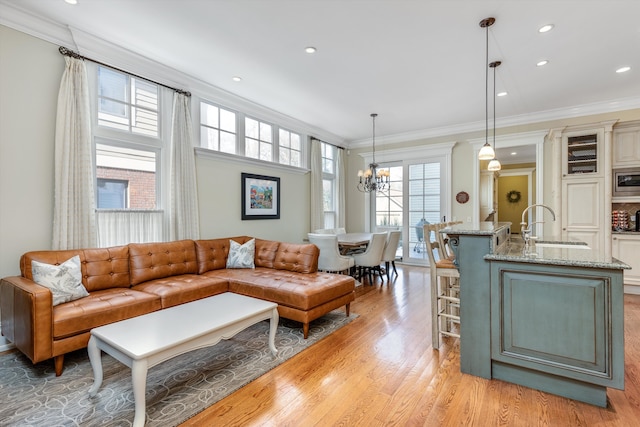 living room with light wood-style floors, recessed lighting, ornamental molding, and an inviting chandelier
