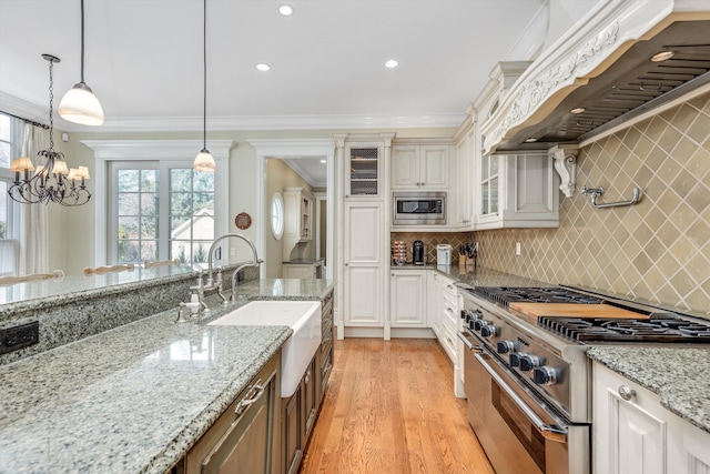 kitchen with a sink, custom exhaust hood, stainless steel appliances, ornamental molding, and glass insert cabinets