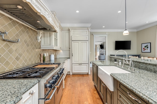 kitchen with a sink, light wood-style flooring, double oven range, custom exhaust hood, and glass insert cabinets