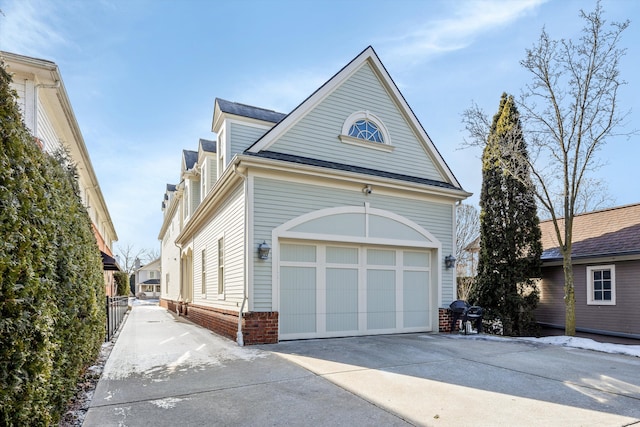 view of side of home featuring a garage, concrete driveway, and brick siding