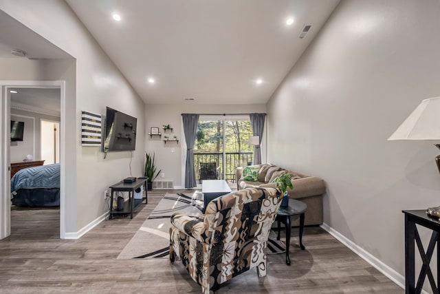 living area with baseboards, vaulted ceiling, wood finished floors, and visible vents