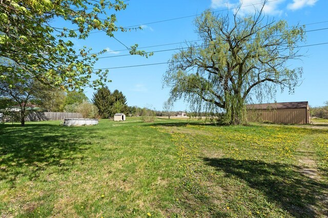 view of yard with fence, an outbuilding, and a shed