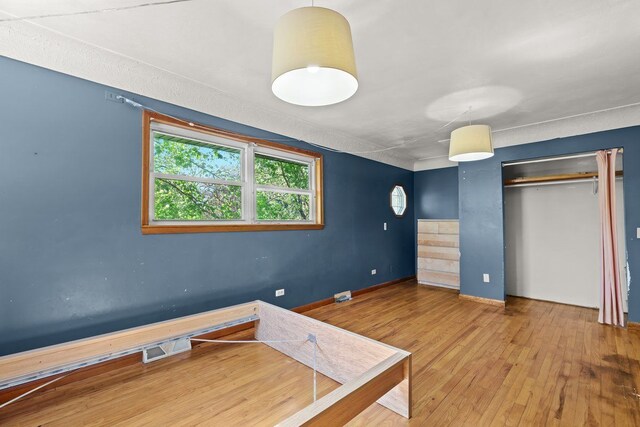 unfurnished bedroom with baseboards, wood-type flooring, and a closet