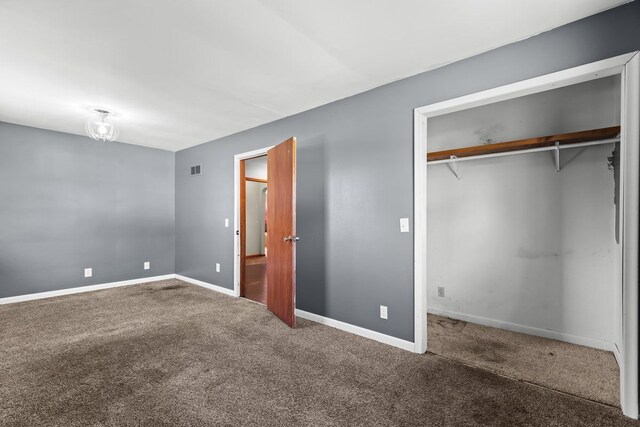 unfurnished bedroom featuring a closet, carpet, baseboards, and visible vents