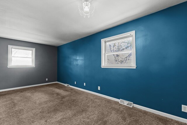 empty room with visible vents, carpet flooring, and baseboards