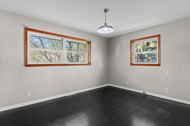 spare room featuring baseboards and dark wood-style floors