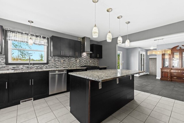 kitchen featuring stainless steel dishwasher, light tile patterned floors, backsplash, and dark cabinets