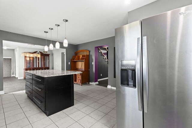 kitchen with stainless steel fridge, baseboards, dark cabinetry, and light tile patterned floors