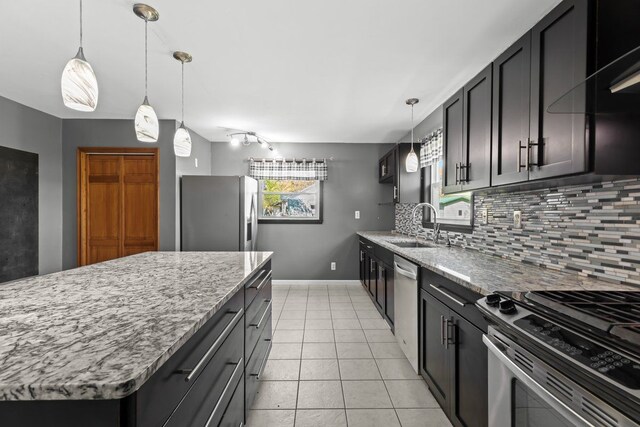 kitchen featuring stainless steel appliances, light stone countertops, a sink, and tasteful backsplash