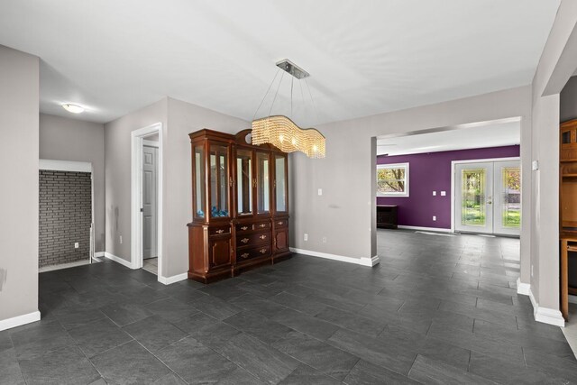 unfurnished dining area featuring baseboards, a notable chandelier, and french doors