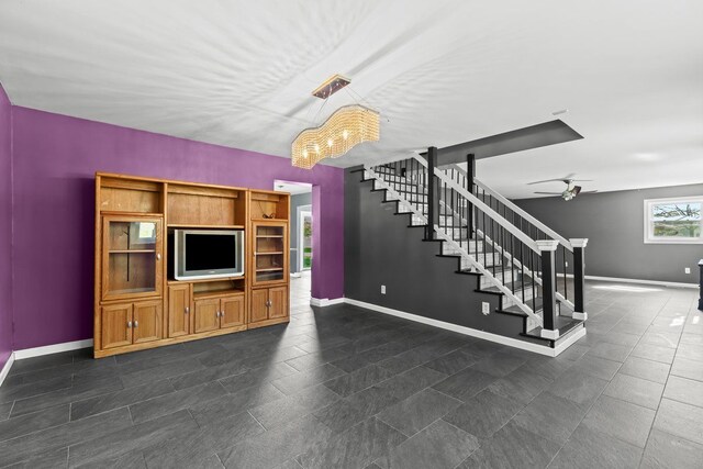 unfurnished living room featuring dark tile patterned flooring, baseboards, ceiling fan, and stairs