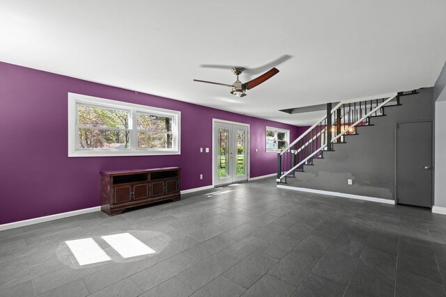 unfurnished living room featuring baseboards, a ceiling fan, stairs, and french doors